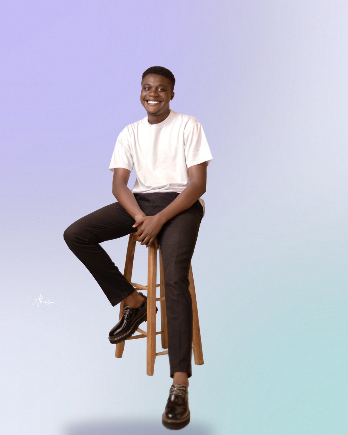 Moses Afolabi seated on a wooden stool, smiling